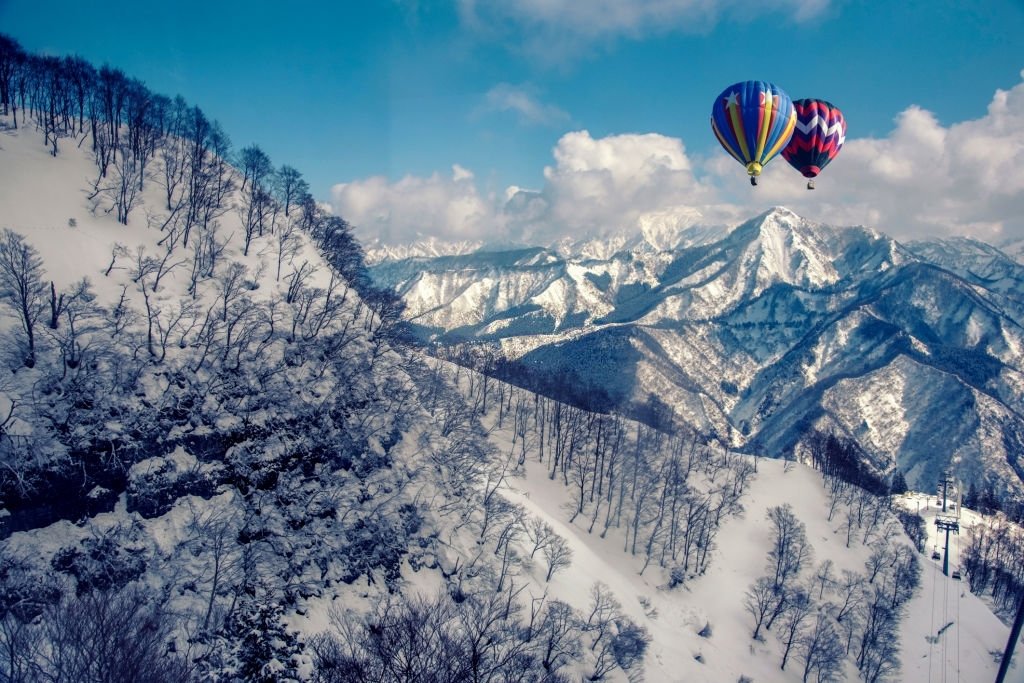 Colorful hot-air balloon flying over snowcapped mountain